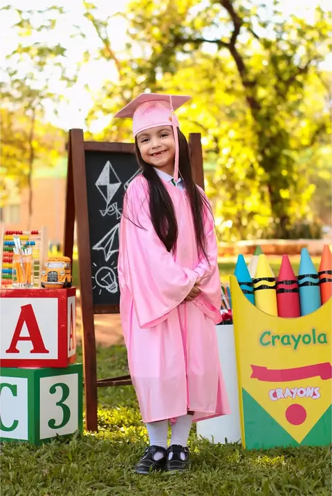 Niña graduada frente a un pizarrón y cubos de letras
