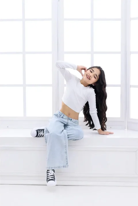 Niña sentada en una ventana blanca