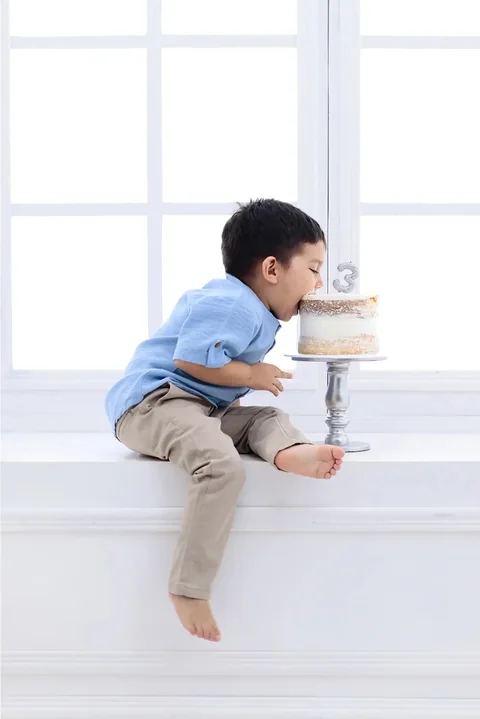 Niño mirando una torta pequeña junto a la ventana